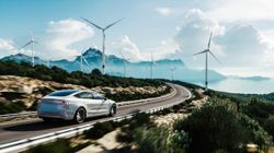 Electric car drive on the wind turbines background. 