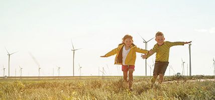Little,Girl,And,Boy,Are,Running,In,Front,Of,Windmills.