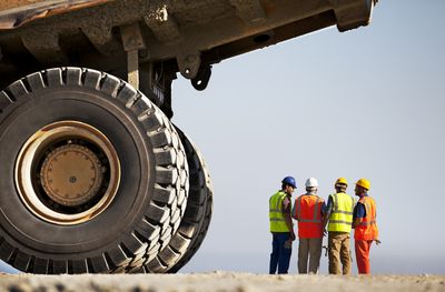 Workers talking by machinery on site Workers talking by machinery on site