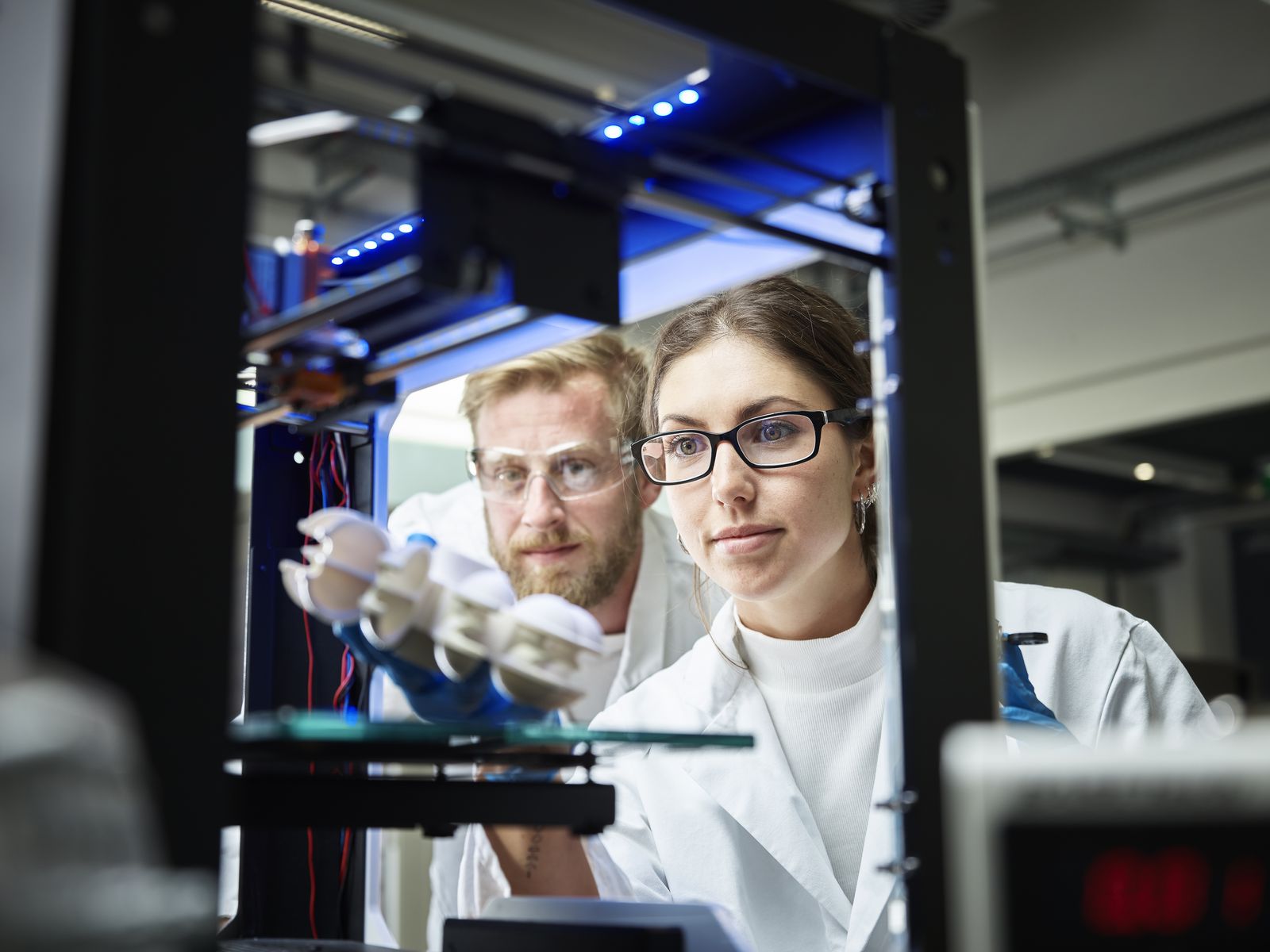 Two technicians looking at turbine wheel being printed in 3d printer