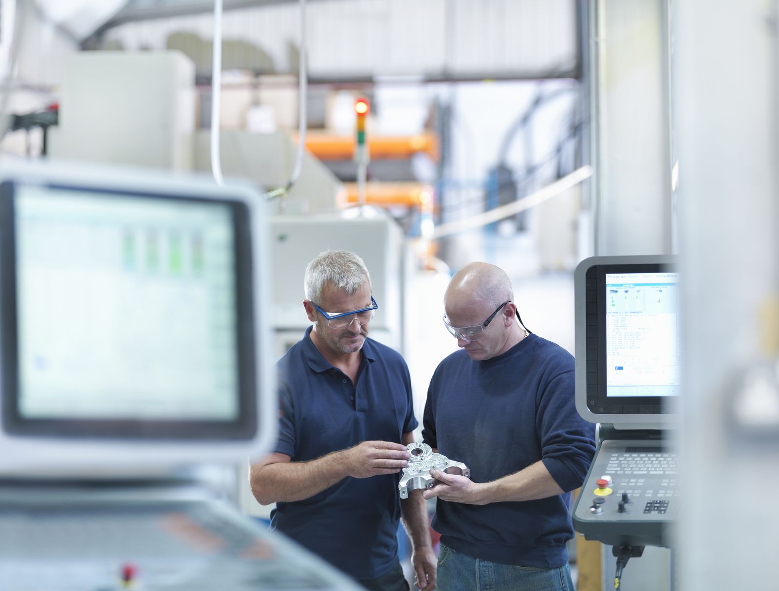 Engineers inspecting complex metal component in factory