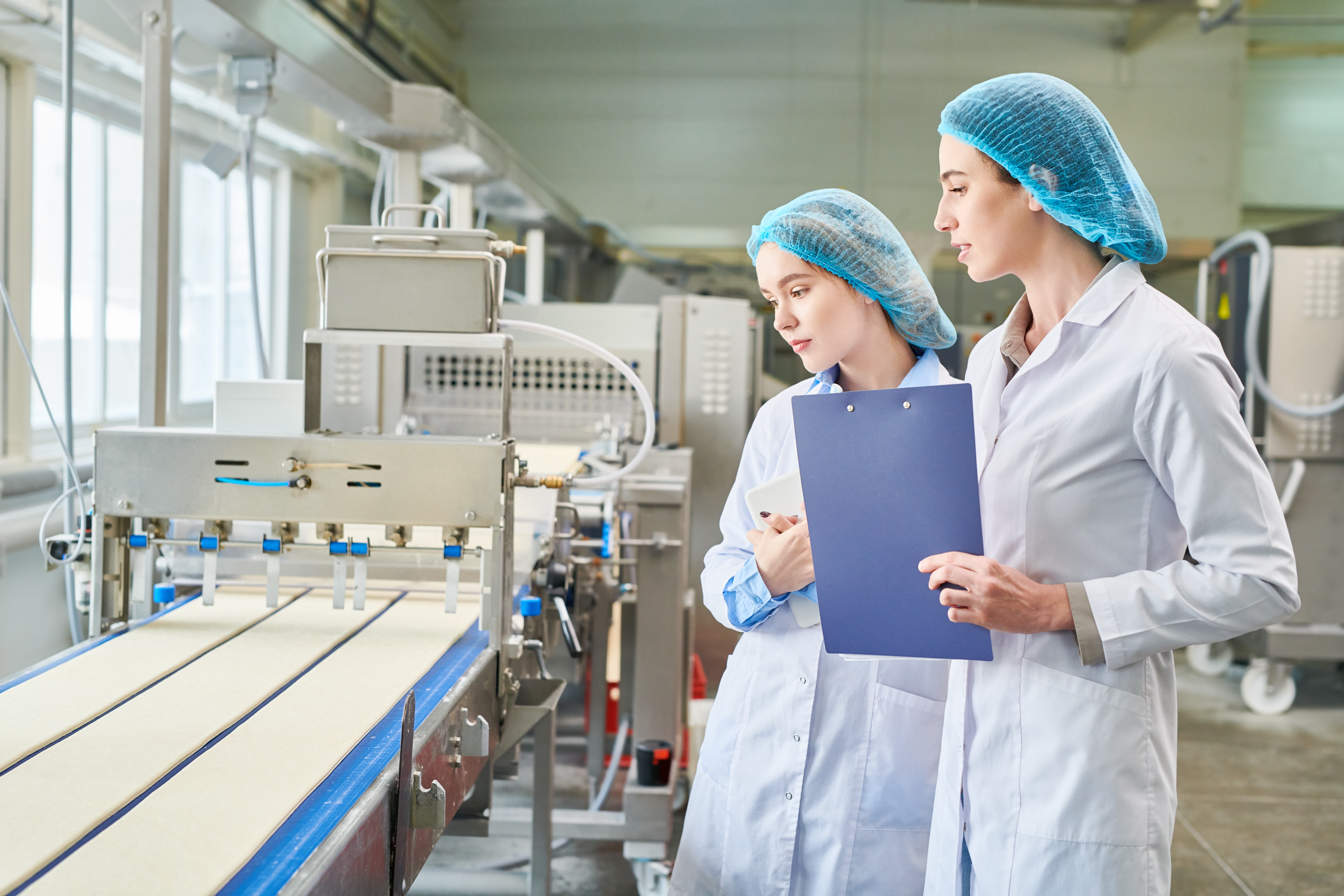 Control specialists of food plant analyzing work of conveyor Control specialists of food plant analyzing work of conveyor