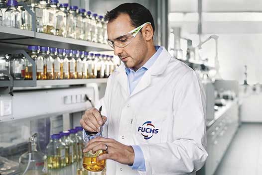 rank Thomas, Head of the “Non water-miscible cutting and quenching fluids” unit and his team ensure the quality of FUCHS cutting fluids. Frank Thomas, Head of Development of FUCHS, standing in the laboratory of FUCHS and holding a container filled with high-grade cutting fluid, a product of FUCHS .
